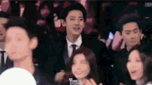 a man in a suit and tie is standing next to a woman in a crowd .