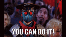 a man in a mask stands in front of a crowd that says you can do it