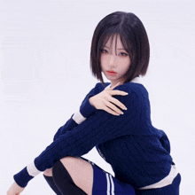 a girl wearing a blue sweater and black knee high socks is squatting down