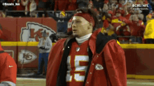 a man in a chiefs jersey stands on a football field