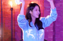 a woman in a blue sweater with horses on it is holding a remote control