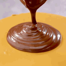 a close up of chocolate being poured onto a yellow surface