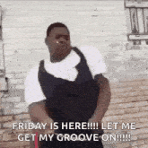 a man is dancing in front of a brick wall and saying `` friday is here ! let me get my groove on ! ''