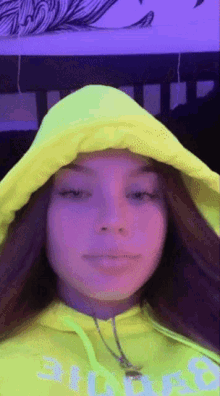 a girl wearing a neon yellow hoodie with the number 8 on it looks at the camera