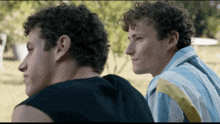 two young men with curly hair are looking at something