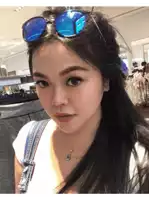 a woman wearing sunglasses and a necklace stands in front of a store that says michael kors