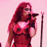 a woman singing into a microphone wearing a red top with black stars on it