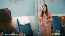a nurse in a pink scrub is crying in a hospital room