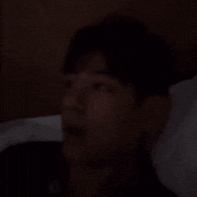a man is laying in bed with his head on a pillow and looking up .