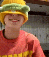 a person wearing a yellow and green hat and a red shirt is smiling .