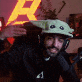 a man wearing headphones and a hat with a baby yoda face on it