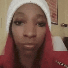 a woman with red hair is wearing a white beanie and a red shirt .