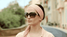 a woman wearing a pink headband and sunglasses