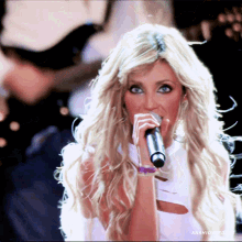 a blonde woman singing into a microphone with the name anahigo on the bottom right