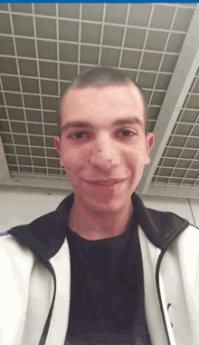 a man wearing a black shirt and a white jacket smiles