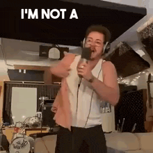 a man is singing into a microphone in a living room while wearing headphones .