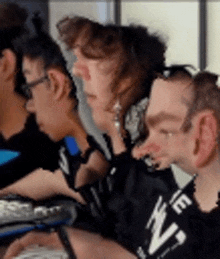 a group of people are sitting at a table looking at a laptop .