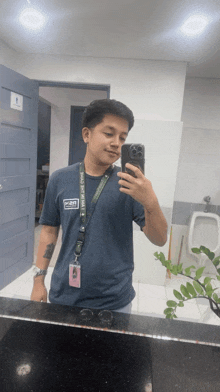 a man taking a picture of himself in a bathroom with a lanyard around his neck that says ' miami ' on it