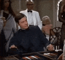 a man in a tuxedo is sitting at a table with a board game .