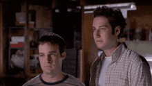 two men in plaid shirts are standing next to each other in a dark room