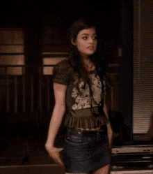a woman is standing in front of a couch in a dark room looking at the camera .