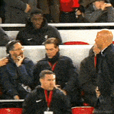 a group of men are sitting in a stadium watching a game and one of them has a nike jacket on