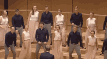 a man in a suit stands in front of a choir of people