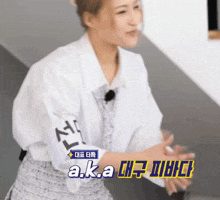 a woman wearing a white shirt with a sticker on the sleeve that says a.k.a