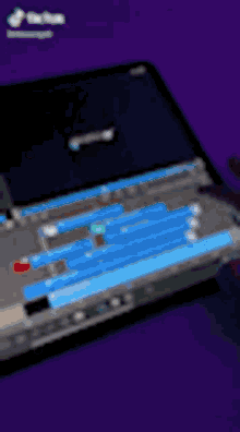 a laptop is sitting on a purple surface with a blue screen