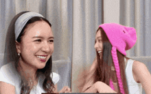 a woman wearing a pink hat with the letter a on it smiles next to another woman