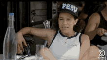 a woman wearing a perv hat sits at a table