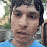 a close up of a man 's face with wet hair and a blue shirt
