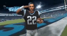 a football player wearing number 22 salutes while holding a football