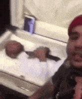 a man in a red hat is taking a selfie with a coffin in the background .