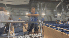 a man in a blue shirt with the number 4 on it leans on a railing