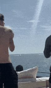 a man without a shirt is standing on a boat in the ocean