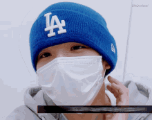 a man wearing a blue la hat and a white mask
