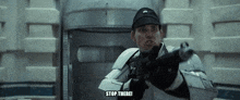 a man in a military uniform is pointing a gun and says " stop there "