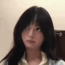a close up of a girl 's face with long black hair and a tie .