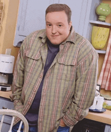 a man in a plaid shirt is smiling in a kitchen
