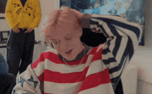 a person with pink hair is wearing a red white and blue striped sweater .