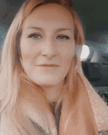 a woman with long blonde hair wearing a scarf and earrings