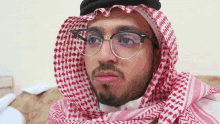 a man wearing glasses and a scarf looks at the camera .