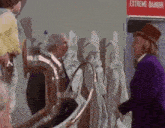 a man in a purple suit and top hat stands in front of a sign that says extreme danger