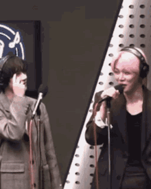 a man with pink hair is singing into a microphone while another man looks on