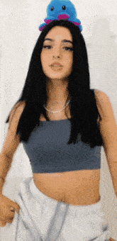 a woman in a crop top has a stuffed animal on her head