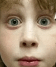 a close up of a child 's face with a surprised expression on his face .