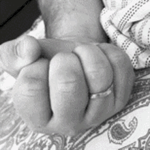 a black and white photo of a person 's fist with a wedding ring on it