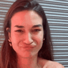 a woman is making a funny face in front of a striped wall .