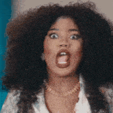 a woman with curly hair is sticking out her tongue and making a surprised face .